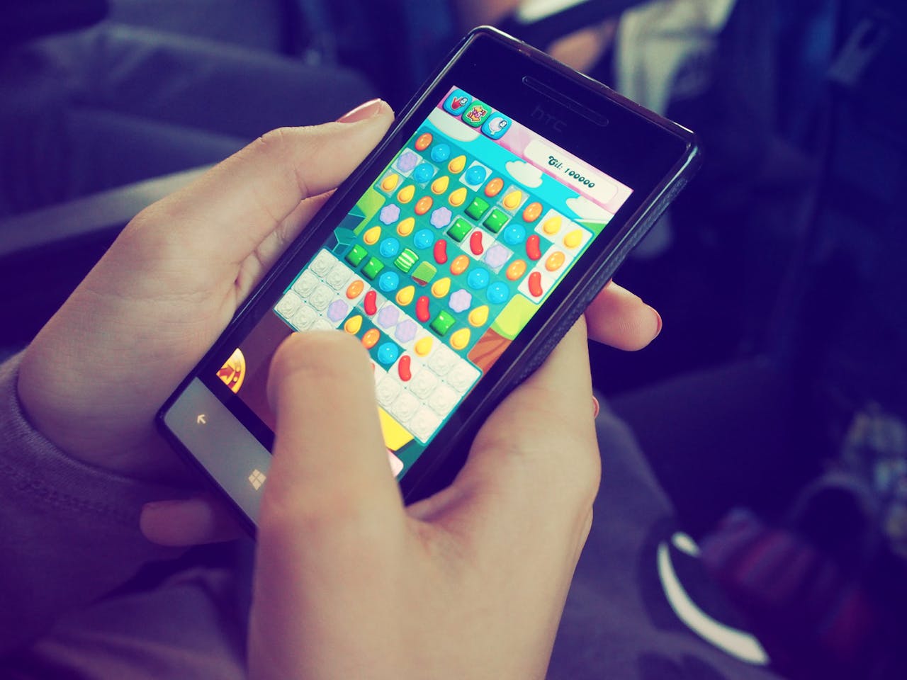 Crafting Captivating Headlines: Your awesome post title goes here Hands holding a smartphone with a colorful puzzle game on the screen, displaying modern technology.